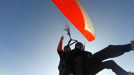 Tourist playing paragliding guided by a pilot