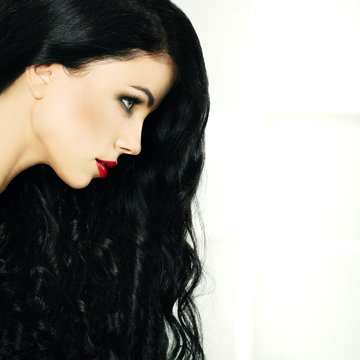 Girl with make-up red lips and beautiful black hair on white