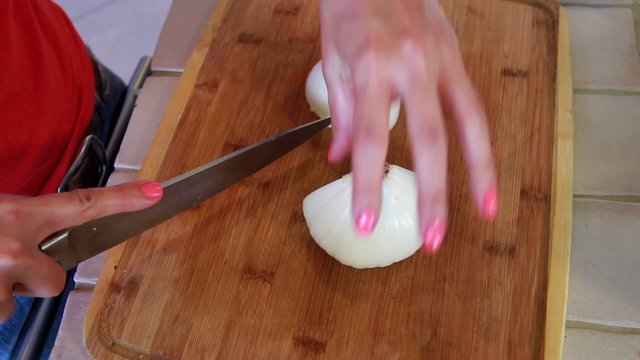 Female chef hands cutting a white onion