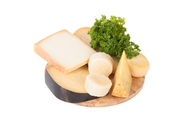 Different cheeses and a bunch of parsley lying on a board isolat