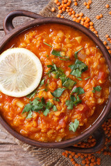 Red lentil soup with lemon and fresh herbs vertical. top view