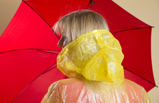 Woman In Yellow Poncho Holding Red Umbrella