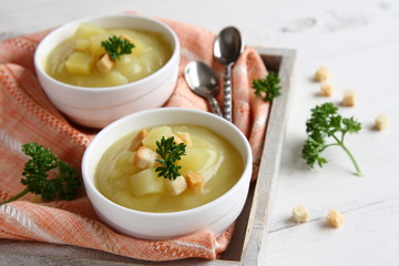 Creamy sweet potato soup with croutons and parsley in white bowl