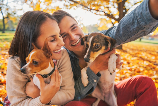 Smiling young couple with dogs outdoors in autumn park