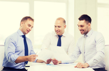 Obraz premium smiling businessmen with papers in office