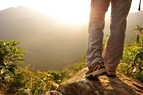 woman hiker legs stand on mountain peak rock 