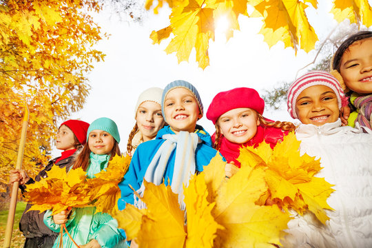 Many smiling kids with rake and yellow leaves