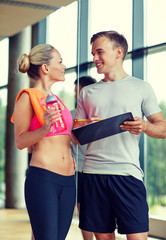 smiling young woman with personal trainer in gym