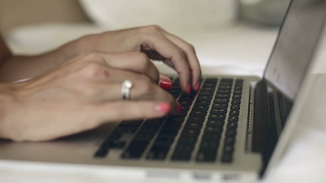 Fingers typing text on the MacBook's keyboard.