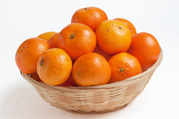 Clémentines et leurs feuilles dans une corbeille sur fond blanc