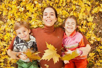 Mother and children playing outdoor with autumn leaves