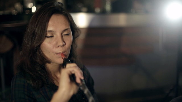 Girl enjoying smoking hookah in a night cafe