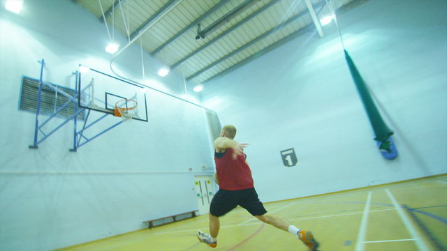 Basketball player runs down the court and slam dunks