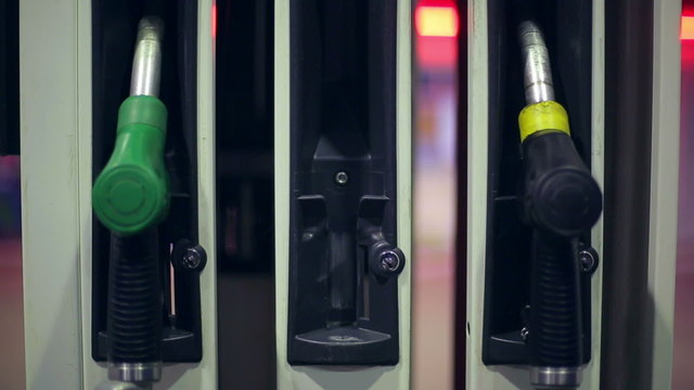 Filling station. A hand returns a fuel nozzles at a station