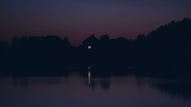 Lonely ascetic house on the lake at night