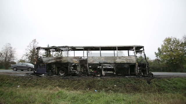 Burned-out passenger bus on the side of the road