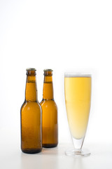 Two brown beer bottles and a full glass of beer.