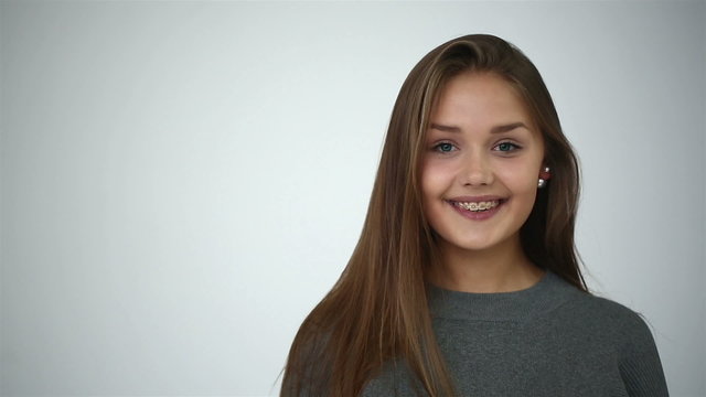 Young girl with braces on teeth throws back her head.