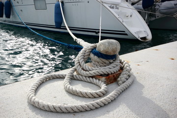 yacht rope mooring on iron bollard on marina quay