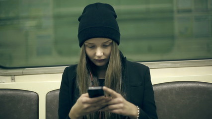 Teen girl rides the subway at night and used smartphone - Powered by Adobe