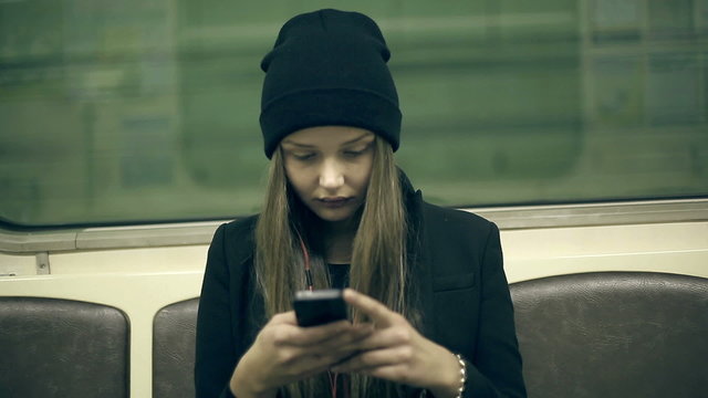 Teen girl rides the subway at night and used smartphone