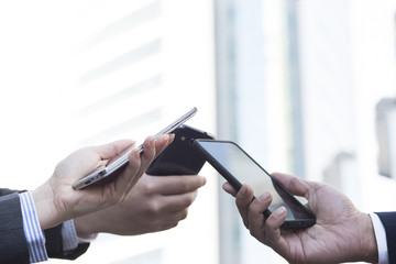 Three businessmen that have a cell phone