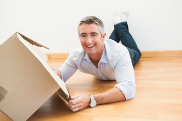 Happy man lying on floor with box looking at camera