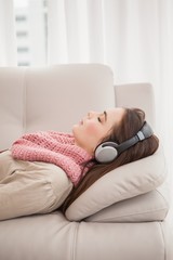 Pretty brunette listening to music on the couch