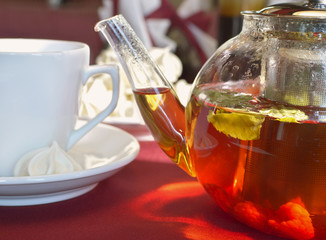 Glass kettle with berry tea and cup