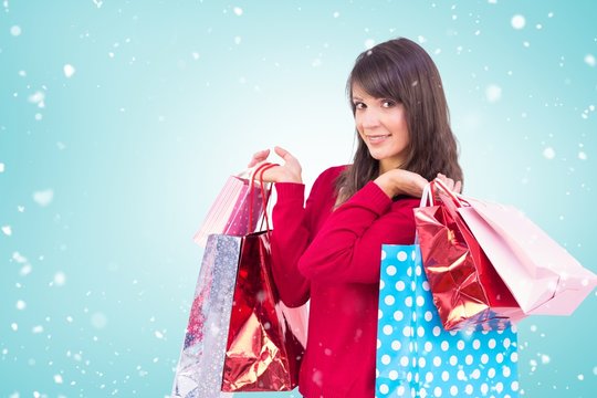 Composite image of smiling brunette holding shopping bags