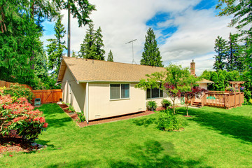 Fenced back with green lawn and  trees.