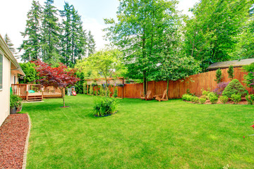 Fenced backyard with green lawn and sitting area