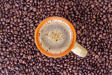 Orange cup of coffee on a background coffee beans