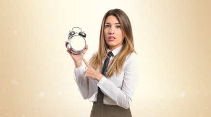 Young businesswoman holding an antique clock over white backgrou