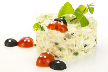 Olivier salad decorated with tomato in the shape of ladybugs