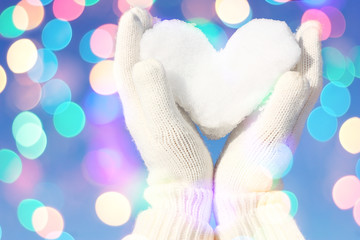 Hands in white gloves holding snow heart