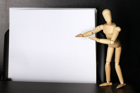 Wooden mannequin points to blank paper