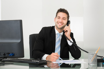 Businessman Discussing Over Documents On Telephone At Desk
