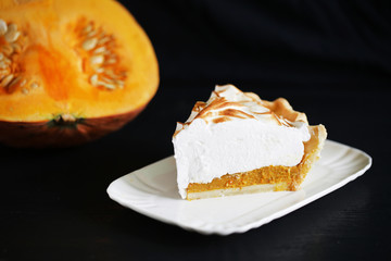 Pumpkin pie slice with meringue and squash on black, isolated
