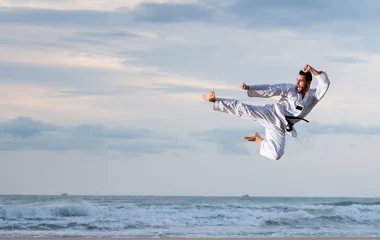 Crédence de cuisine en verre imprimé Arts martiaux Homme sautant pour pratiquer le coup de pied d& 39 arts marcial