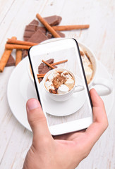 Hands taking photo hot cocoa with smartphone.