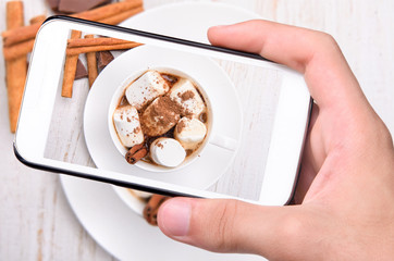 Hands taking photo hot cocoa with smartphone.