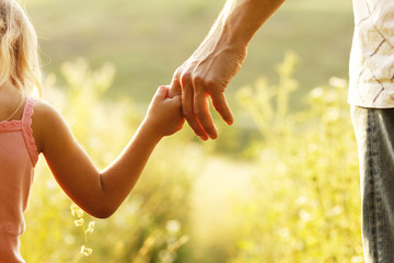 parent holds the hand of a small child