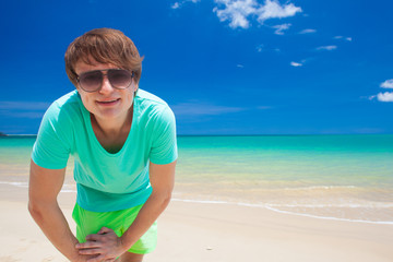 young man in sunglasses smiling at beach