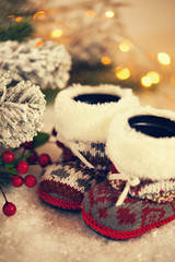 Baby Slippers Near Christmas Tree On Snowy Background