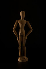 wooden mannequin making gesture on a black background