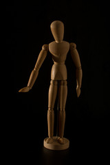 wooden mannequin making gesture on a black background