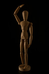wooden mannequin making gesture on a black background