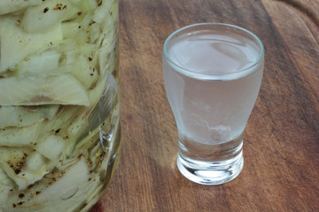 Vodka shot in front of a jar of herrings.