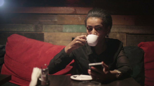 Black woman drinking hot coffee and use smartphones